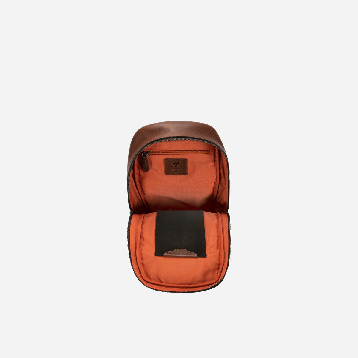 Brosnan One Strap Backpack in brown, open showing orange lining and inner pockets
