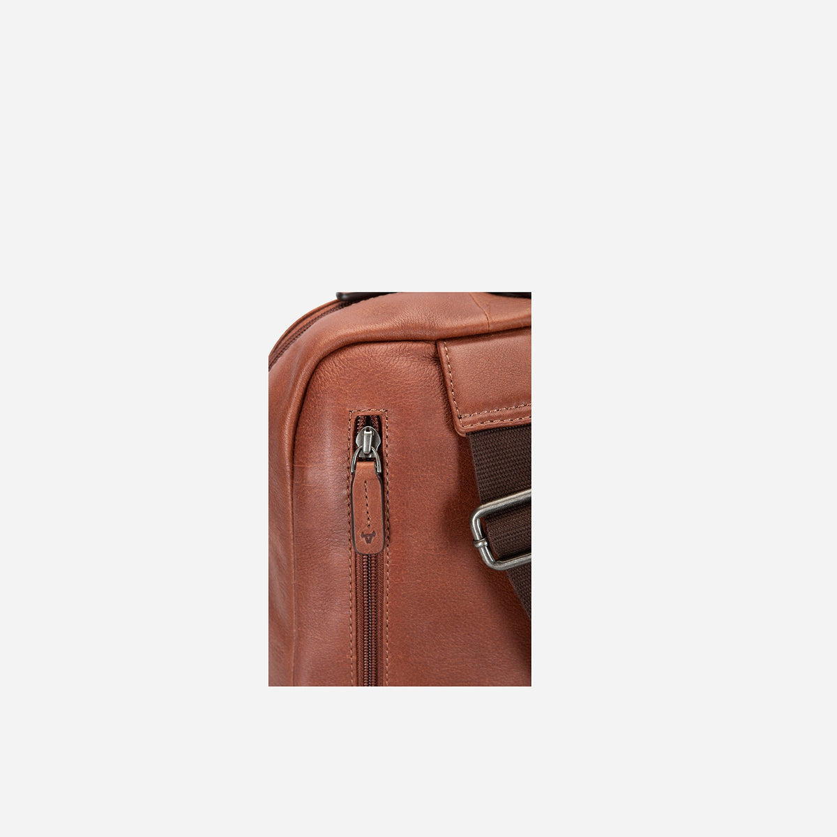 Close-up of the side zip and strap anchor on the copper pebbled leather Kudu sling backpack