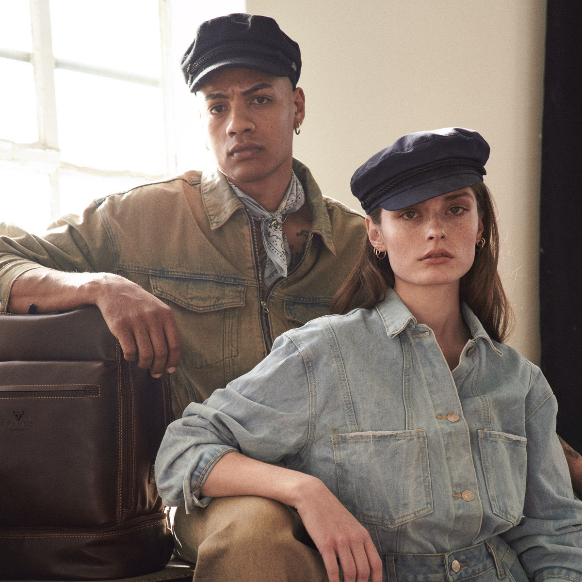 Brown James Laptop Backpack beside a couple in denim and caps at a studio window
