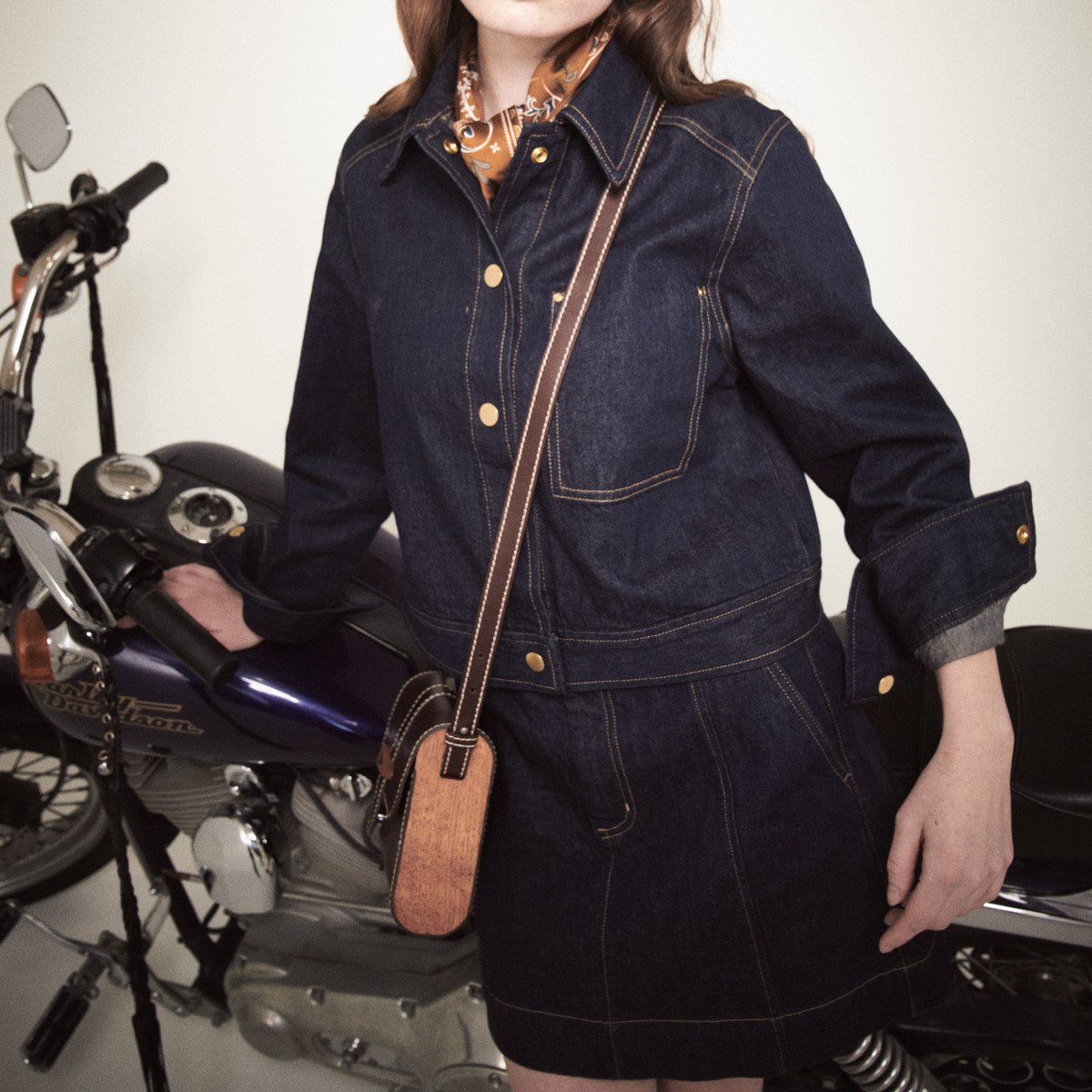 Sally brown satchel on a long leather strap, wooden side panel at the hip of a denim skirt