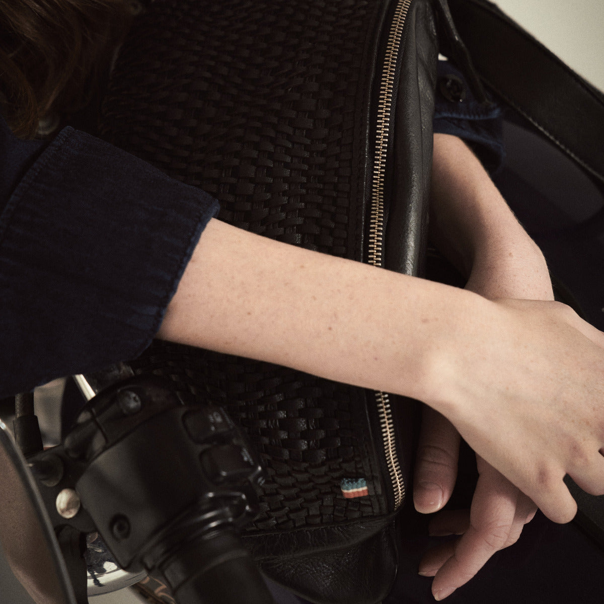 Close-up of the Bell Waist Bag in black woven leather with zip and tricolour tab