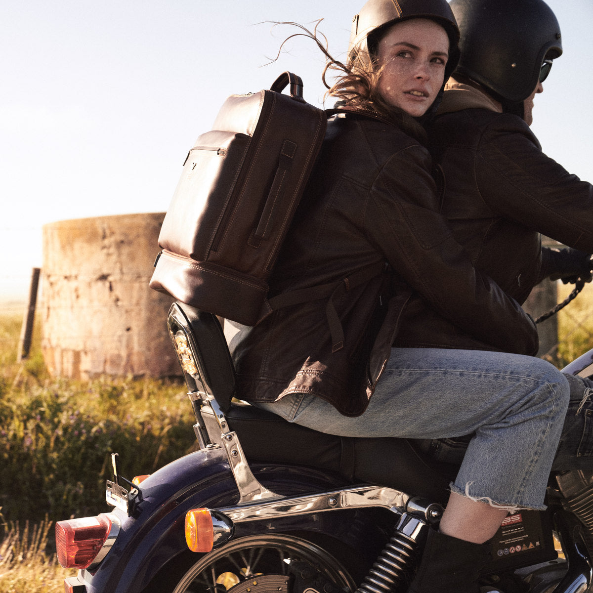 James Laptop Backpack in brown on a pillion rider's back, water tank and grass behind