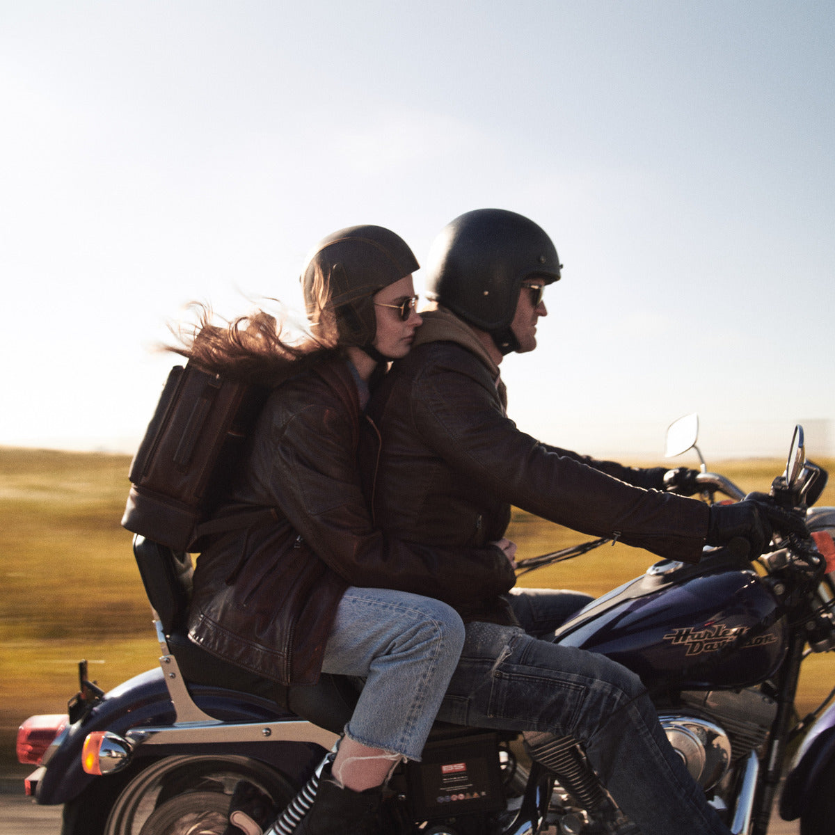 Couple riding a motorbike, the woman wearing the brown James Laptop Backpack