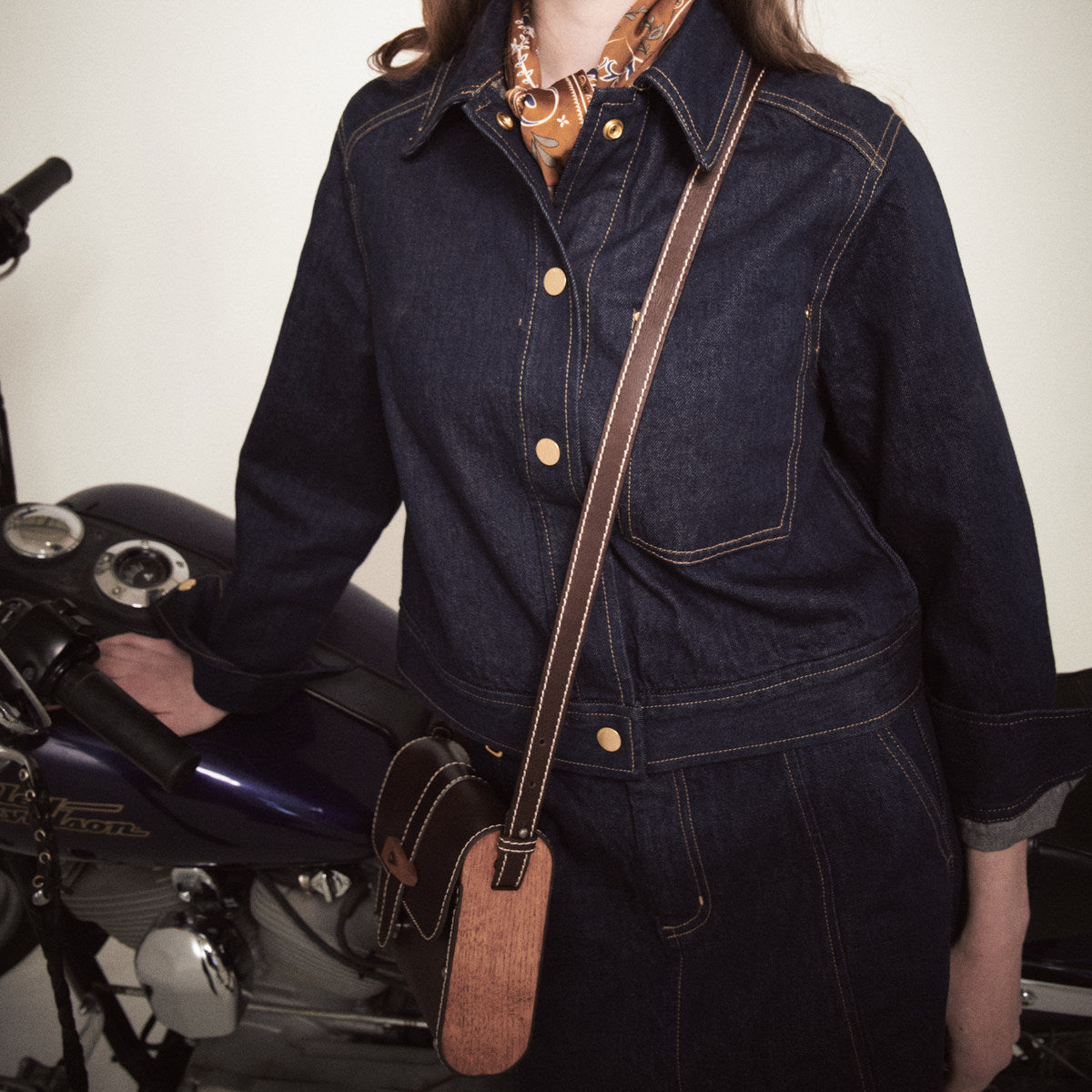 Sally Wood Panel Satchel in brown worn crossbody over a navy denim jacket beside a motorbike